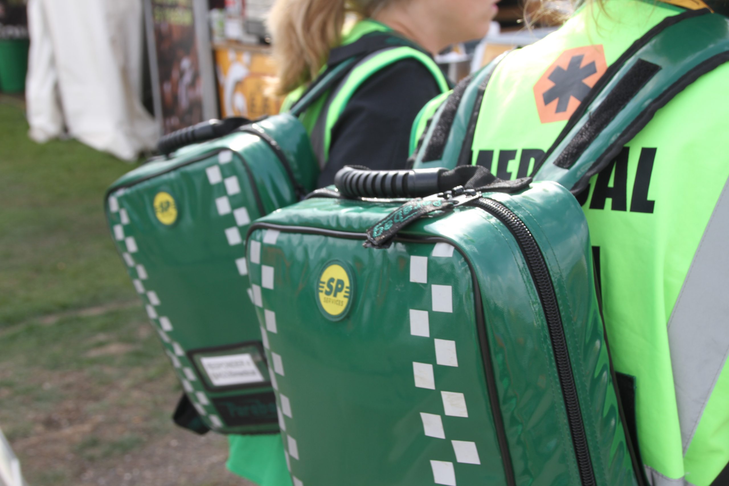 An image of two medical staff at an event responding with green medical rucksacks
